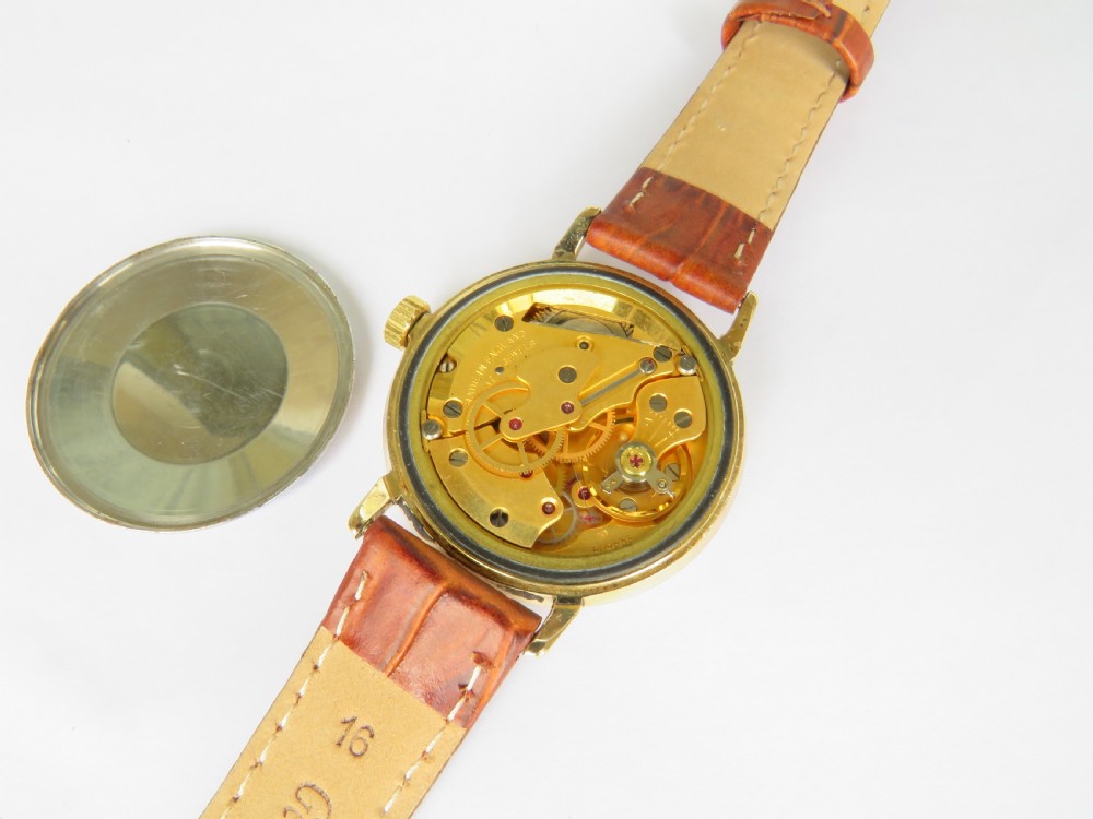 A 1960s Smiths Astral wristwatch featuring a gold-plated case, a cream dial with Arabic numerals at twelve, three, six, and nine, and a brown leather strap. View III
