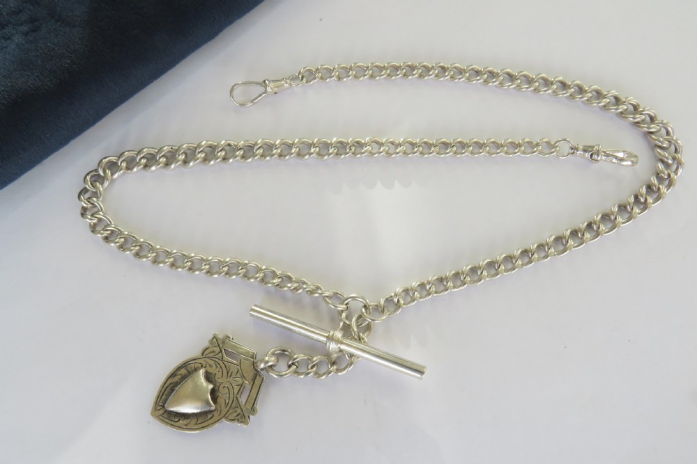 A silver double curb link Albert watch chain necklace featuring a central T-bar, swivel clasps, and an engraved shield fob. View II