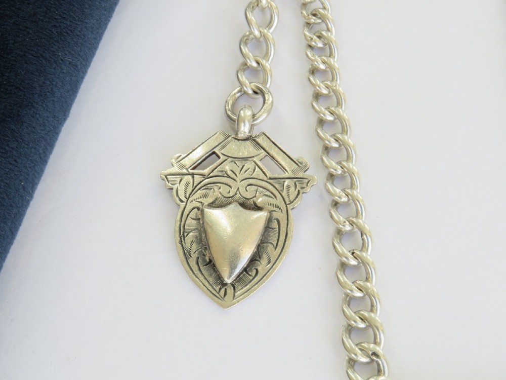 A silver double curb link Albert watch chain necklace featuring a central T-bar, swivel clasps, and an engraved shield fob. View III