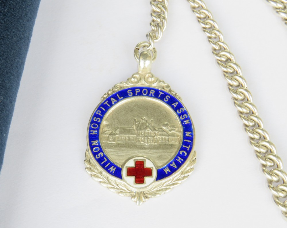 A sterling silver curb-link pocket watch chain featuring a T-bar fastener, swivel clasp, and a circular blue and red enamel sports medallion. View II