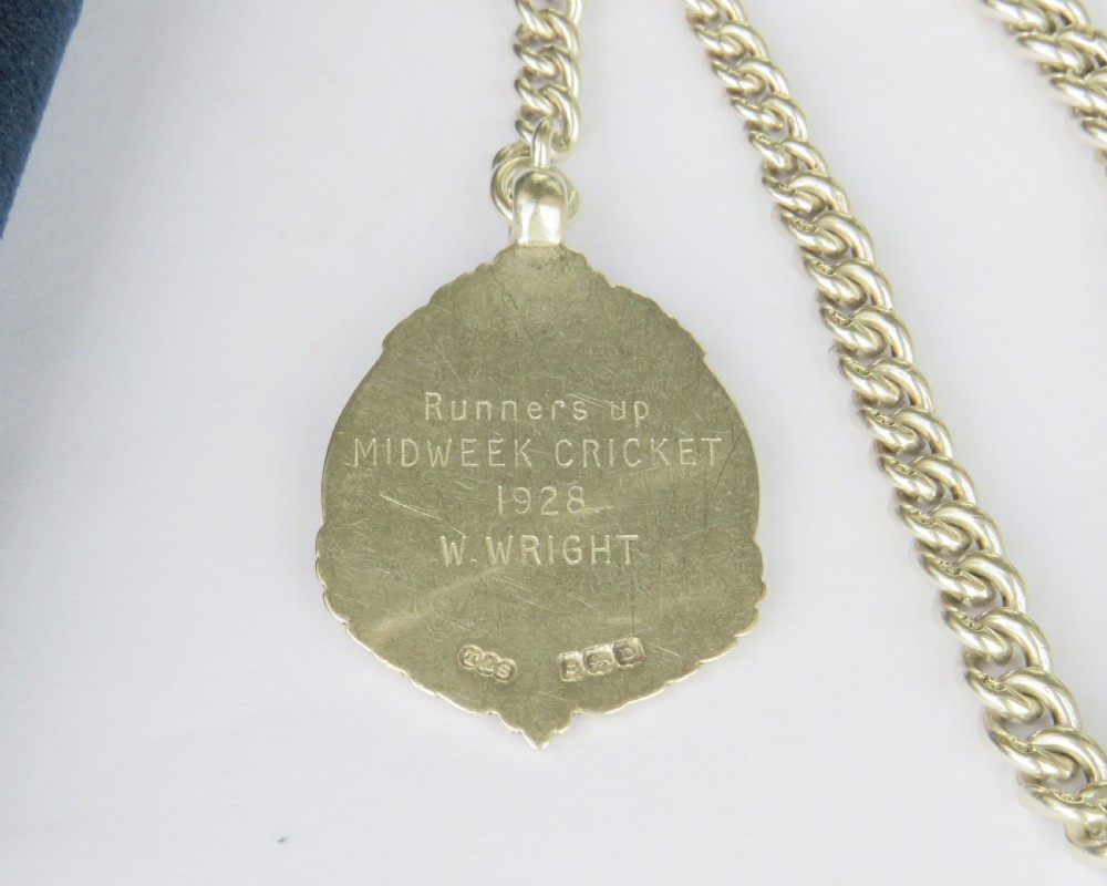 A sterling silver curb-link pocket watch chain featuring a T-bar fastener, swivel clasp, and a circular blue and red enamel sports medallion. View III