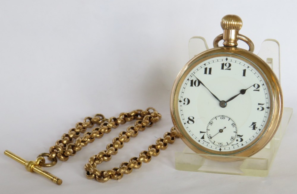A 1930s gold-toned open-face pocket watch featuring a white enamel dial with Arabic numerals, a sub-seconds register, and a connected Albert chain with T-bar.