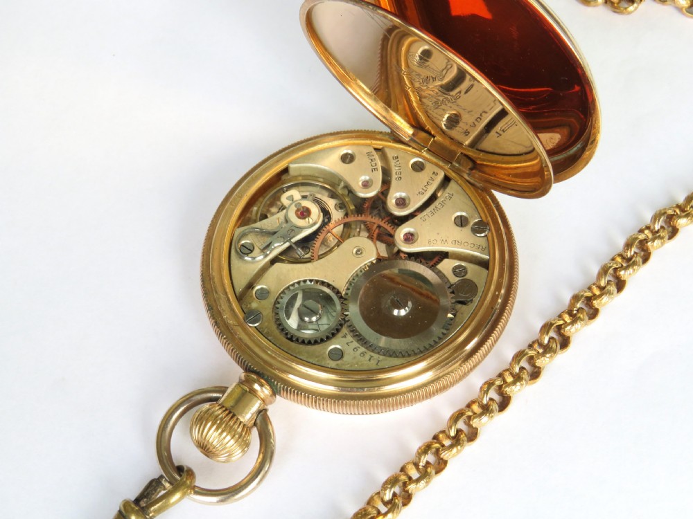 A 1930s gold-toned open-face pocket watch featuring a white enamel dial with Arabic numerals, a sub-seconds register, and a connected Albert chain with T-bar. View IV