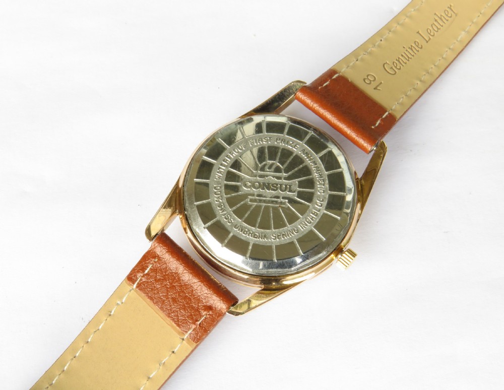 A 1960s gents Consul Dermaphile automatic wristwatch with a gold-tone case, champagne dial, faceted border indices, date window, and brown leather strap. View III