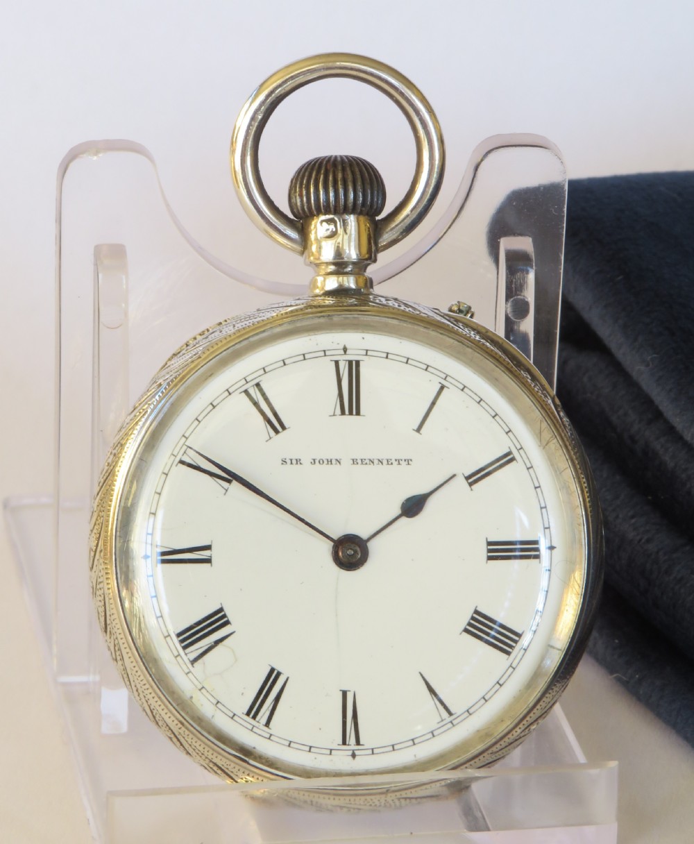 An antique open-face silver pocket watch featuring a white enamel dial with black Roman numerals and an engraved silver case. View II