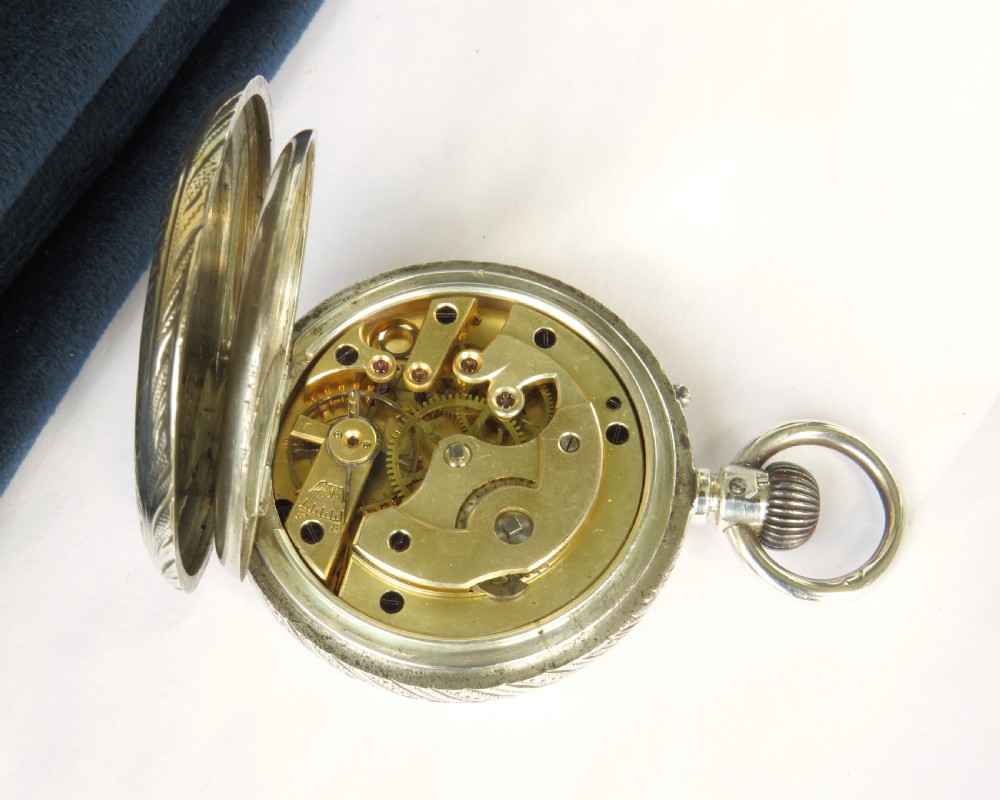 An antique open-face silver pocket watch featuring a white enamel dial with black Roman numerals and an engraved silver case. View IV