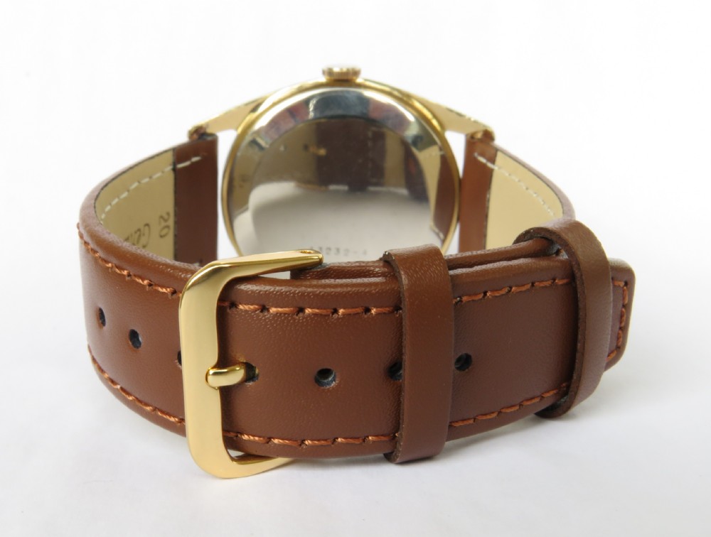A vintage 1950s gents Certina wristwatch featuring a round gold-toned case, cream dial with sub-seconds display, and a brown leather strap. View V