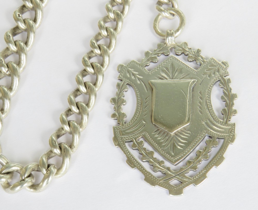 A Victorian sterling silver heavy curb link Albert watch chain featuring a T-bar attachment, swivel clasp, and an engraved shield-shaped fob. View III