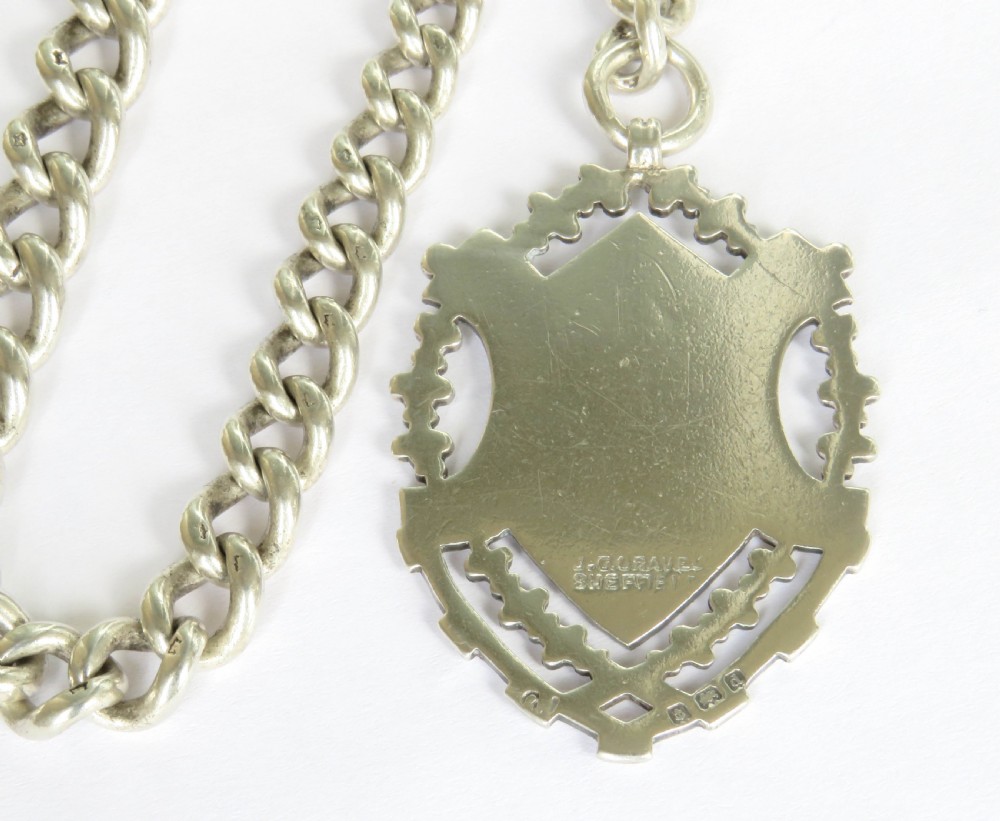A Victorian sterling silver heavy curb link Albert watch chain featuring a T-bar attachment, swivel clasp, and an engraved shield-shaped fob. View IV