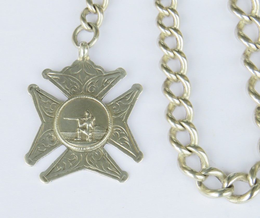 A silver curb link Albert pocket watch chain featuring a T-bar fastener, swivel clasp, and a carved star-shaped fob medallion. View II