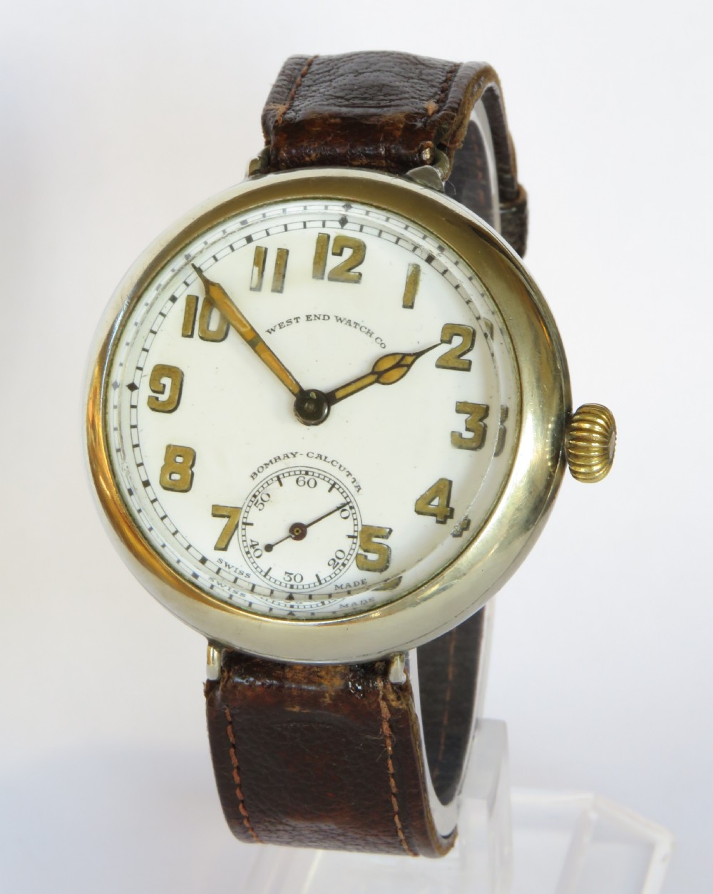 An antique West End Watch Co wrist watch featuring a white enamel dial with Arabic numerals, sub-seconds dial, and a brown leather strap.