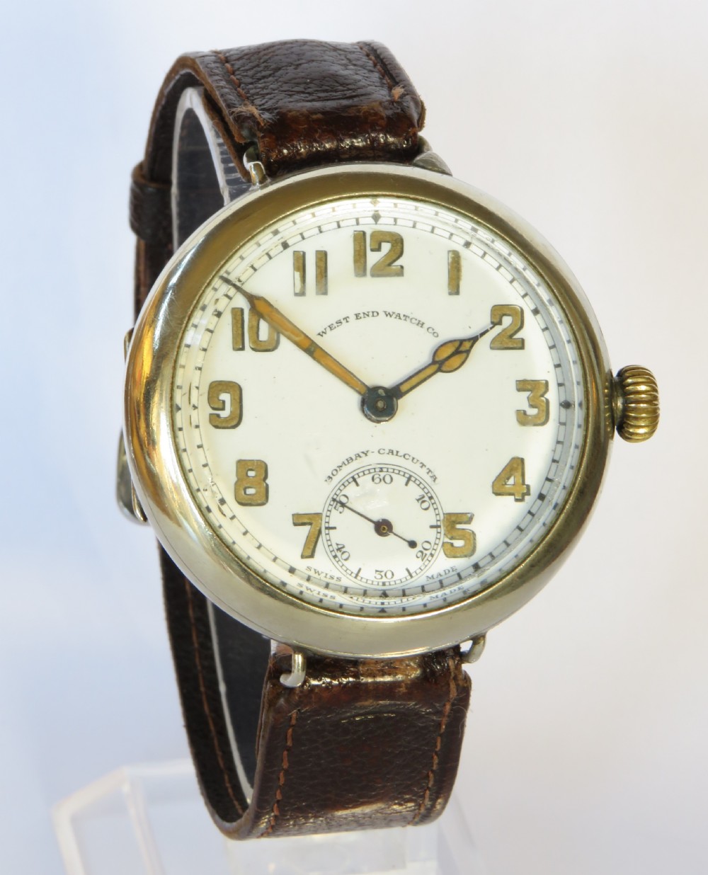 An antique West End Watch Co wrist watch featuring a white enamel dial with Arabic numerals, sub-seconds dial, and a brown leather strap. View II