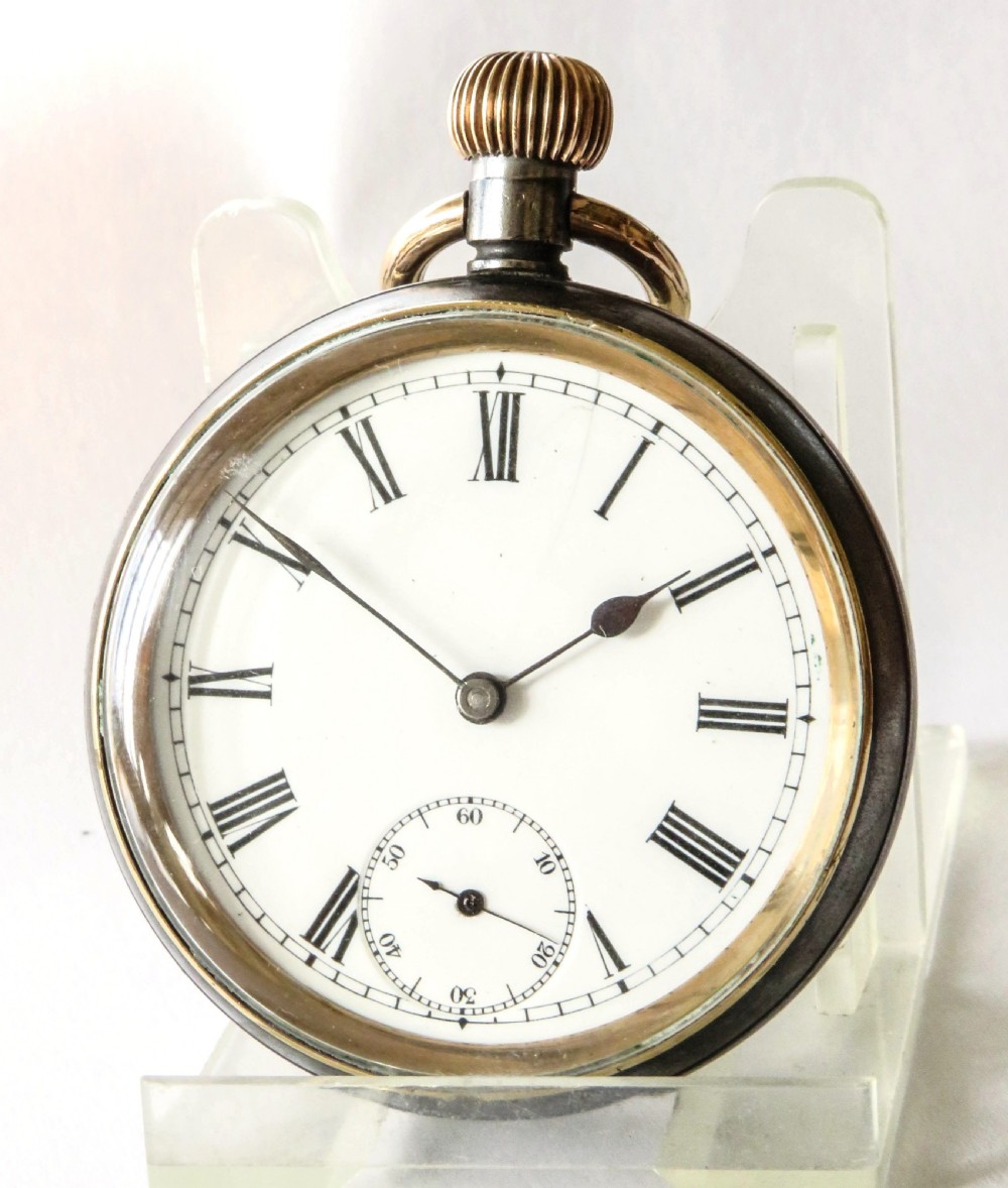 An open-face antique gunmetal pocket watch featuring a white enamel dial with black Roman numerals, gold-toned rim, and a subsidiary seconds sub-dial.