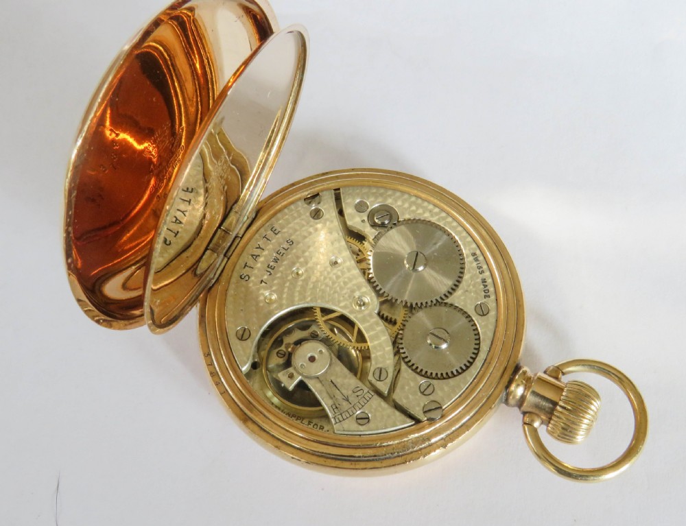 An open-face 1920s gold-coloured pocket watch by Stayte Tavannes featuring a white dial with black Roman numerals and a subsidiary seconds dial. View V