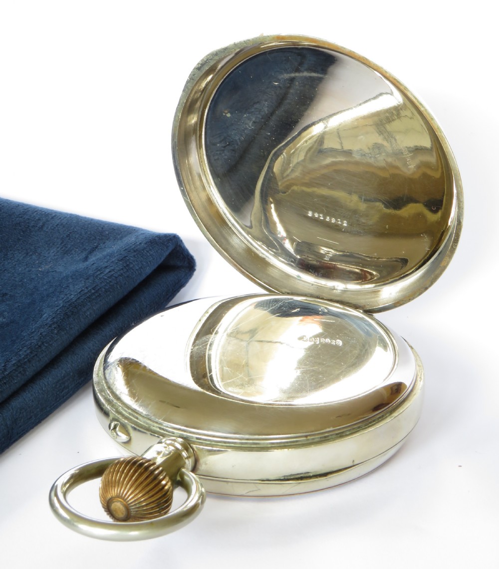 An oversized open-face pocket watch featuring a white enamel dial with black Roman numerals, subsidiary seconds dial, and a metallic casing with top winding loop. View III