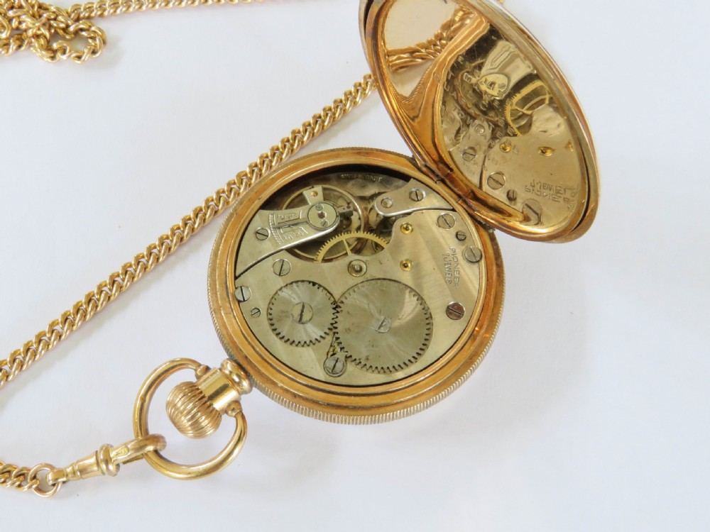 A 1920s gold-toned open-faced pocket watch displaying a white dial, black Arabic numerals, and a gold curb chain with a T-bar. View IV