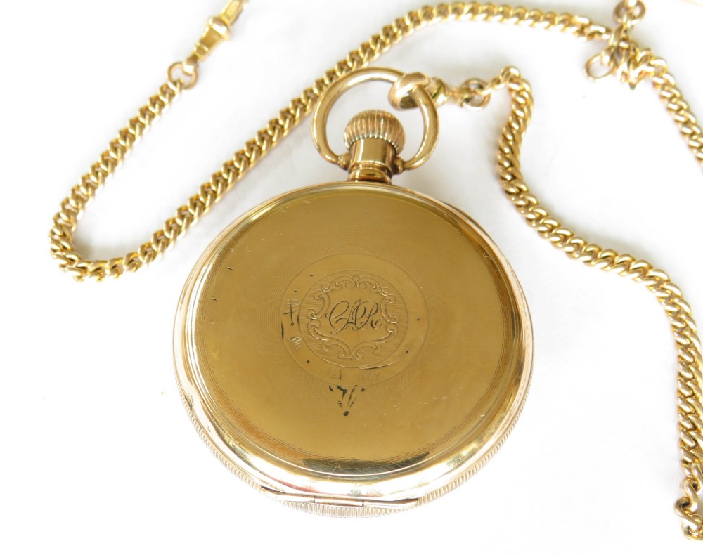 A 1920s gold-toned open-faced pocket watch displaying a white dial, black Arabic numerals, and a gold curb chain with a T-bar. View V