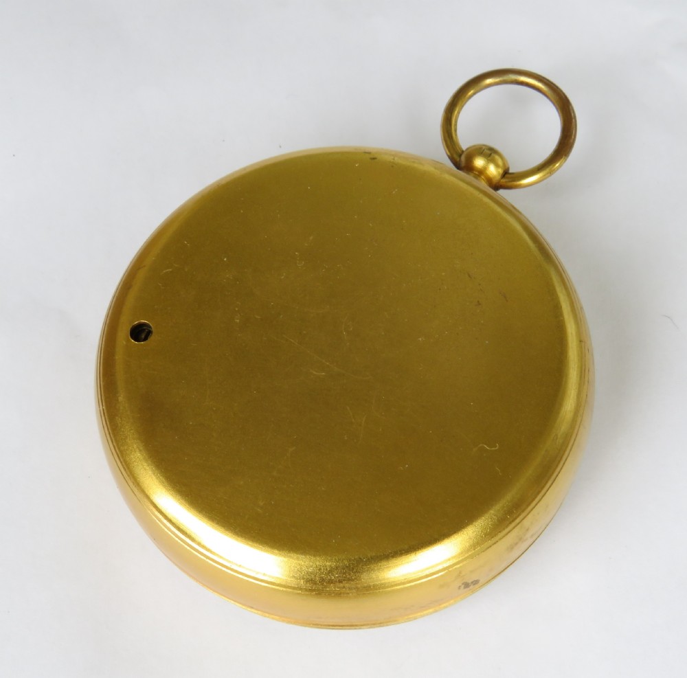 A circular antique brass pocket altimeter featuring a calibrated dial marked in feet and inches, with a top suspension loop. View III