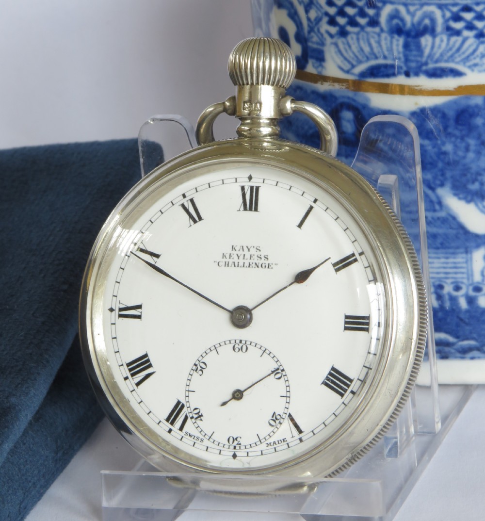 An open-face silver pocket watch with a white enamel dial, black Roman numerals, and a sub-seconds dial.