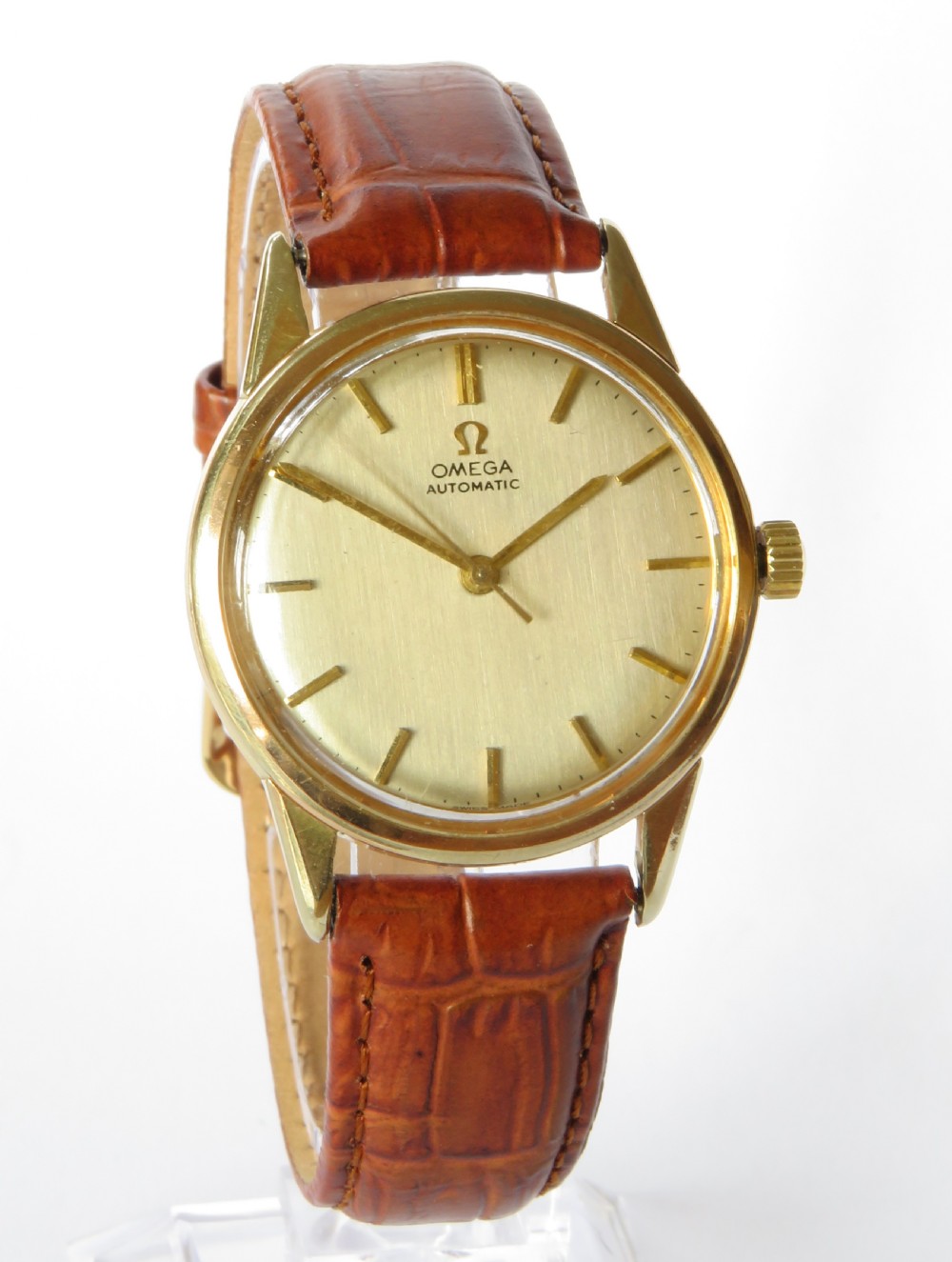 A 1960s Omega automatic wristwatch featuring a champagne dial with gold baton markers and a textured brown leather strap. View II