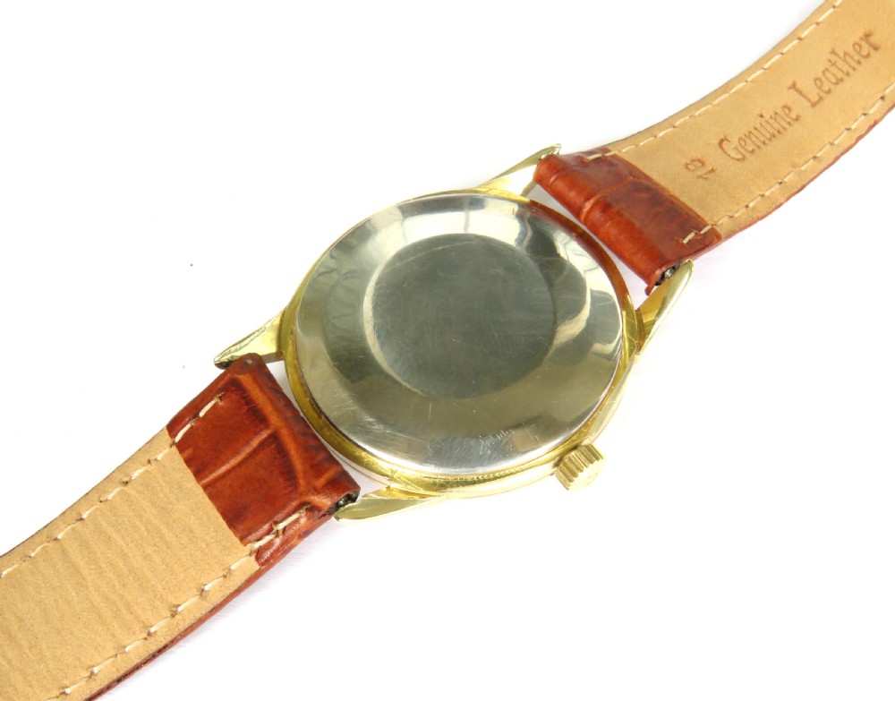 A 1960s Omega automatic wristwatch featuring a champagne dial with gold baton markers and a textured brown leather strap. View IV