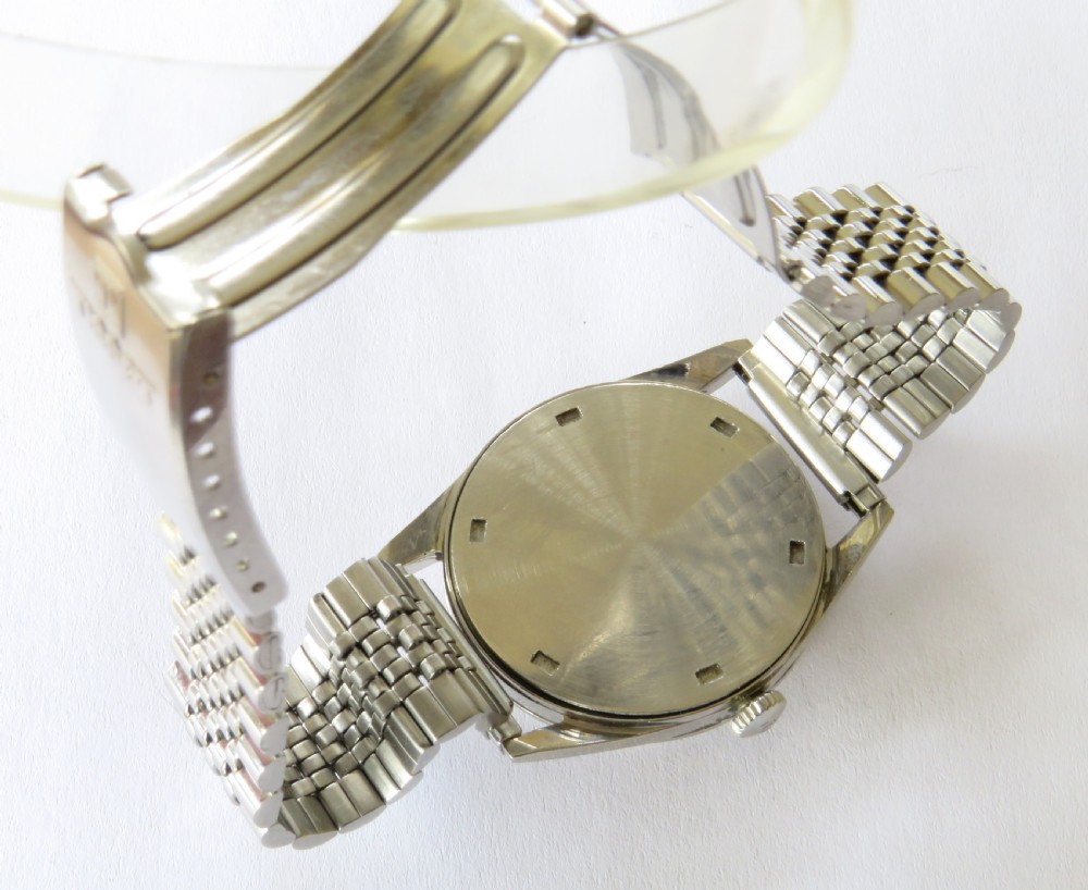 A vintage 1961 Tissot Seastar wrist watch featuring a stainless steel case, patinated cream dial with Arabic numerals, and a multi-link steel bracelet. View IV