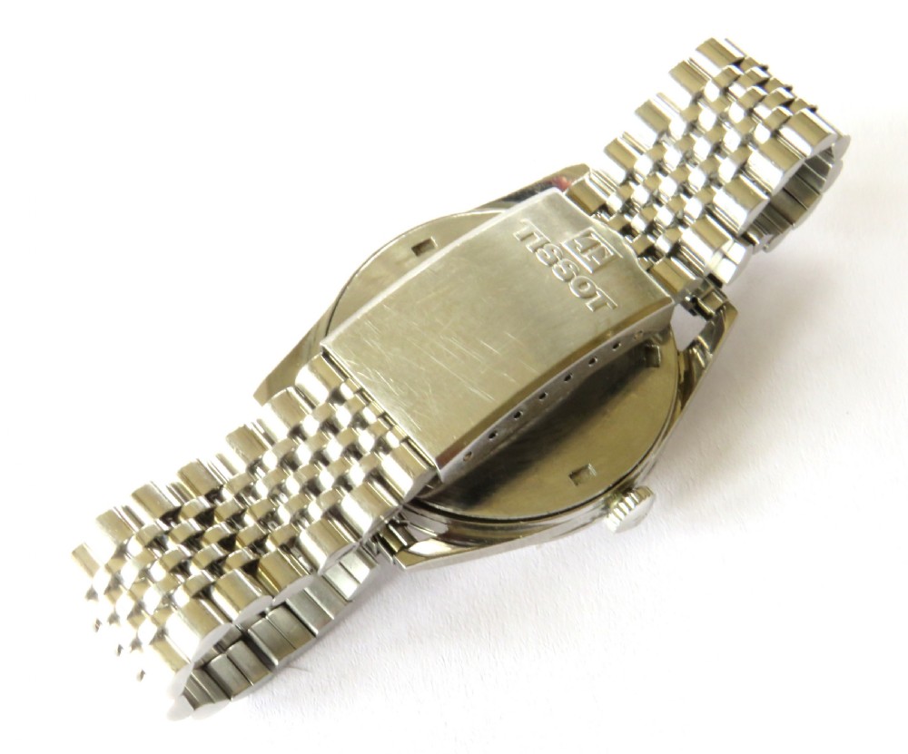 A vintage 1961 Tissot Seastar wrist watch featuring a stainless steel case, patinated cream dial with Arabic numerals, and a multi-link steel bracelet. View V