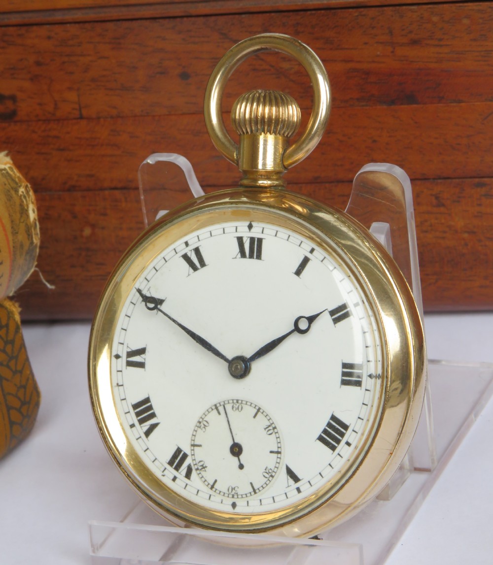 A 1920s open-face gold-toned pocket watch with a white enamel dial, black Roman numerals, and a subsidiary seconds track at six oclock.