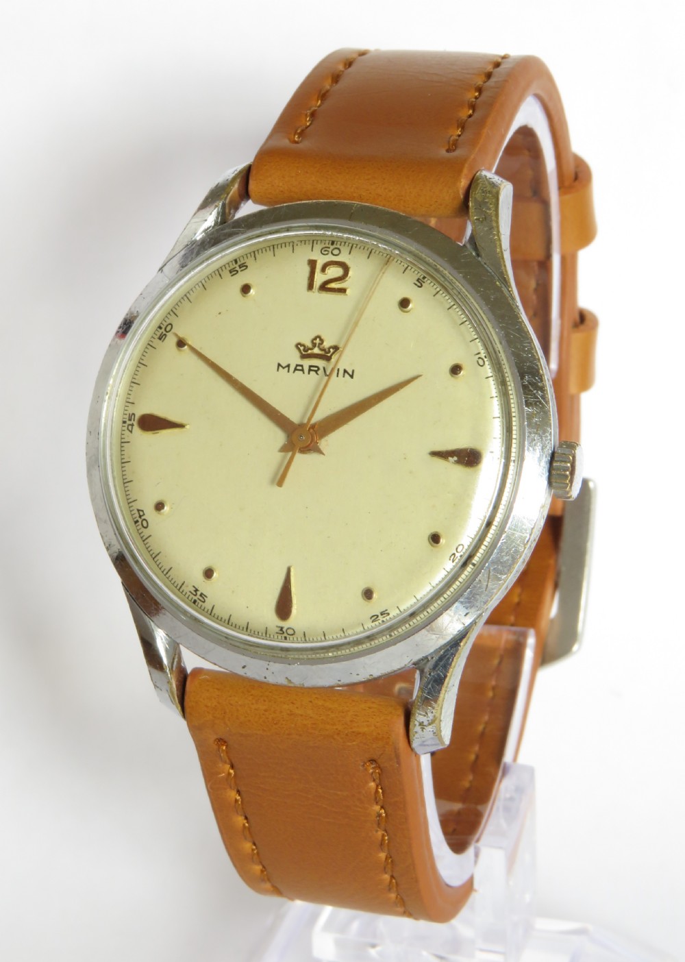A vintage 1950s Marvin gents wristwatch featuring a cream dial with gold-tone markers and a tan leather strap.