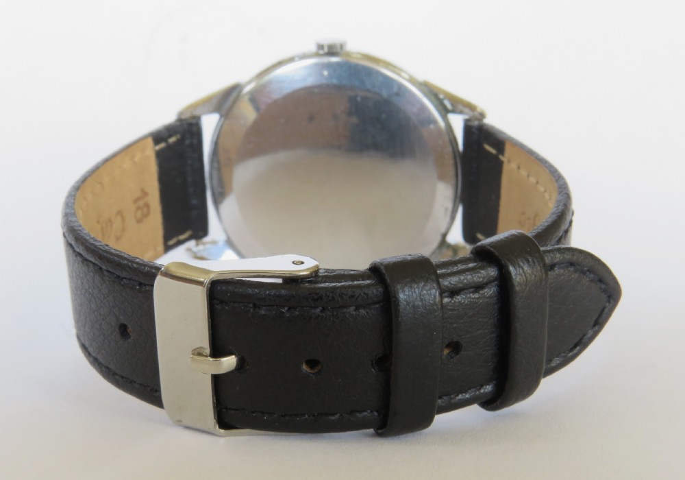A vintage 1950s Dogma Prima gents wristwatch with a cream patinated dial, Arabic numerals, sub-seconds display, and a black leather strap. View V