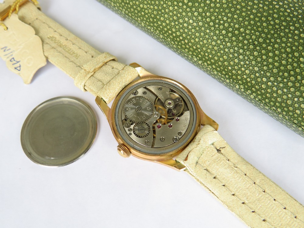 A 1950s gold-plated Lanco mechanical wrist watch with a cream dial and light leather strap resting inside its original green patterned presentation case. View VI