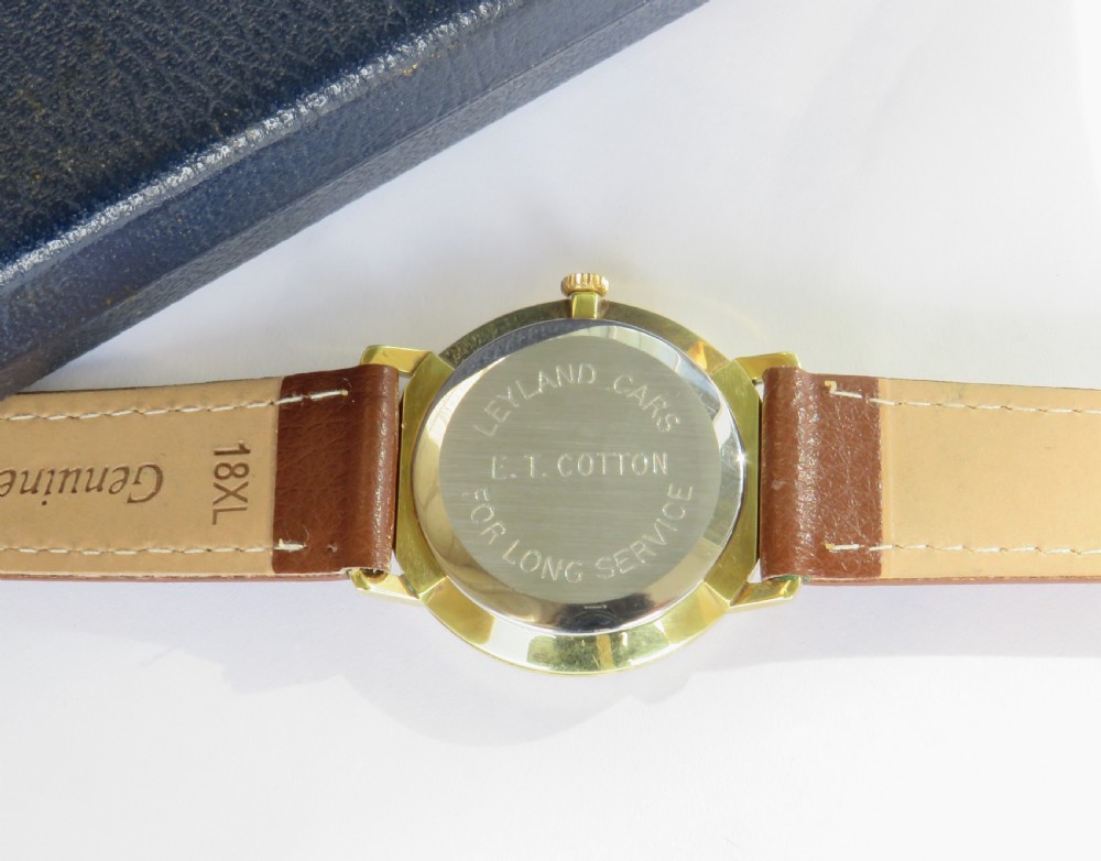 A 1960s gents Garrard wristwatch with a gold-toned case, off-white dial, baton markers, and brown leather strap resting inside a navy blue velvet presentation box. View IV