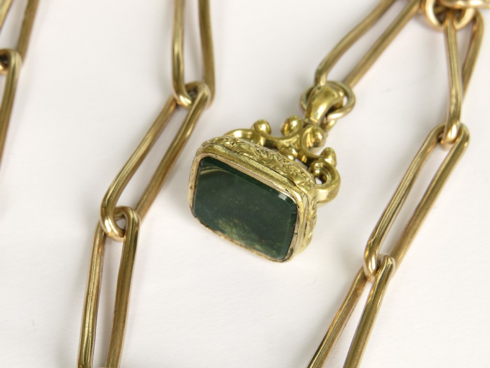 An antique Victorian rolled rose gold watch chain with elongated links, a T-bar attachment, a swivel clasp, and an ornamental fob seal with a green stone. View III