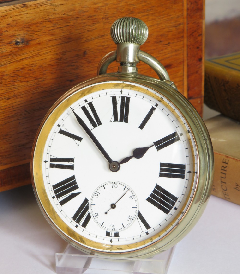 An antique goliath pocket watch featuring a white enamel dial with black Roman numerals, a sub-seconds dial, an onion crown, and a metallic case with a gilded inner bezel.