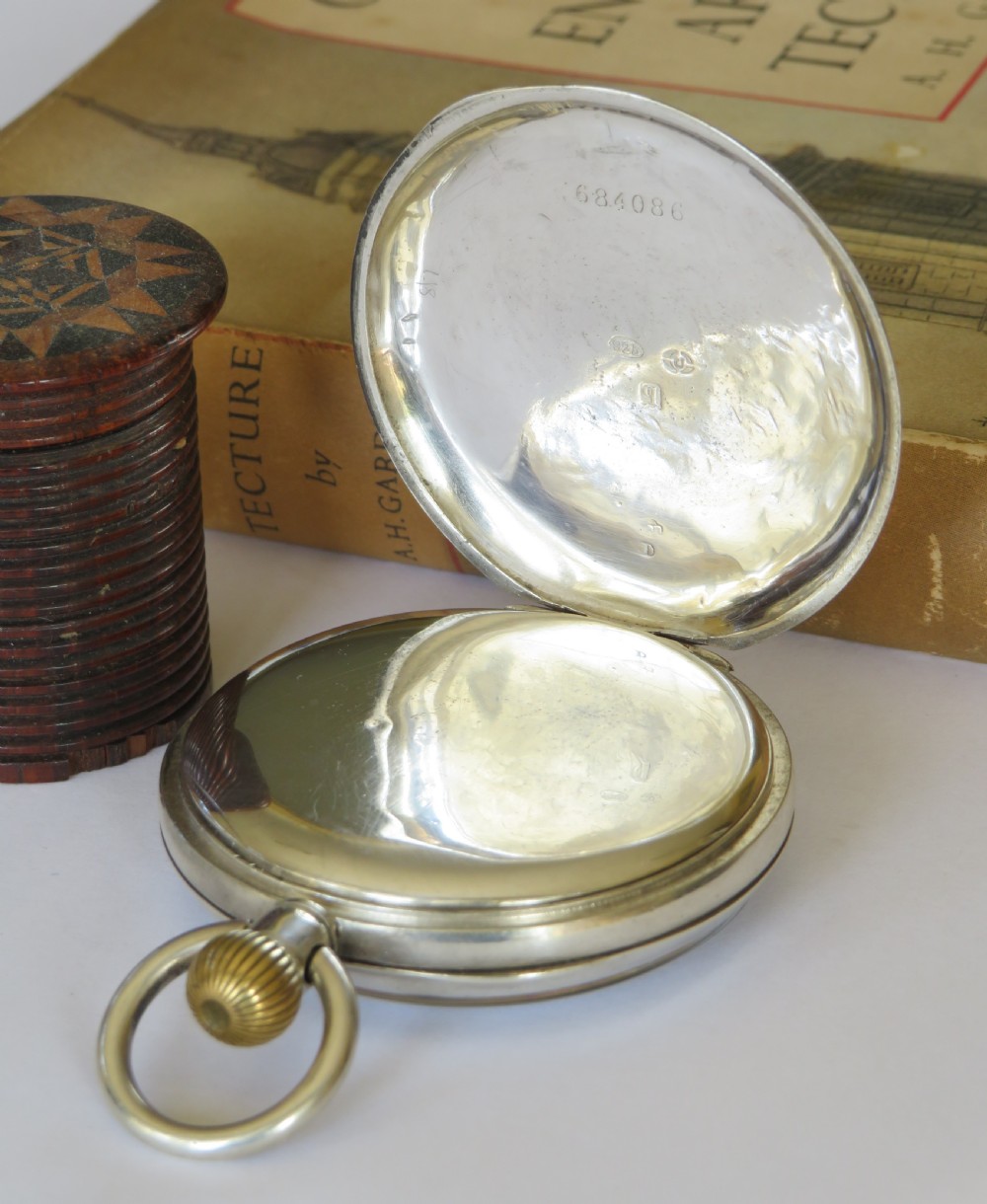 An open-face antique silver pocket watch with a white enamel dial, black Roman numerals, sub-seconds dial, and a ribbed crown. View III