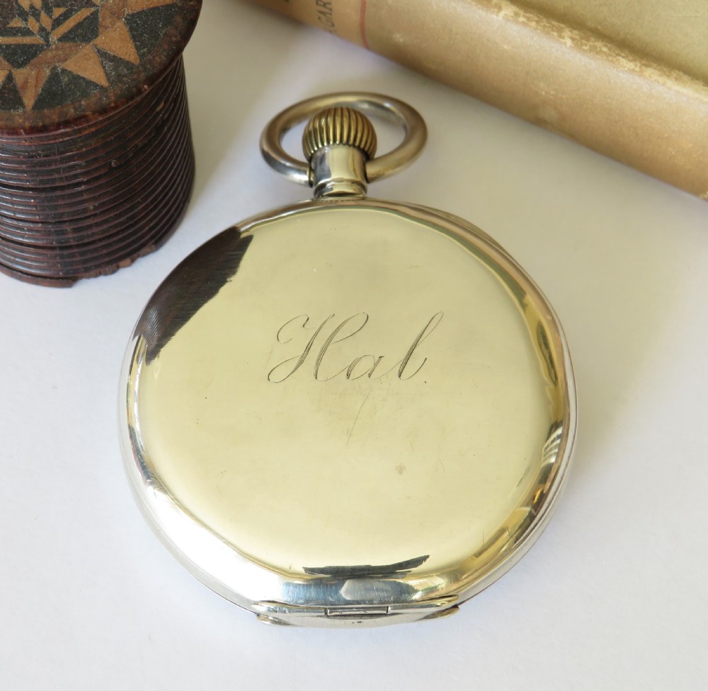An open-face antique silver pocket watch with a white enamel dial, black Roman numerals, sub-seconds dial, and a ribbed crown. View V