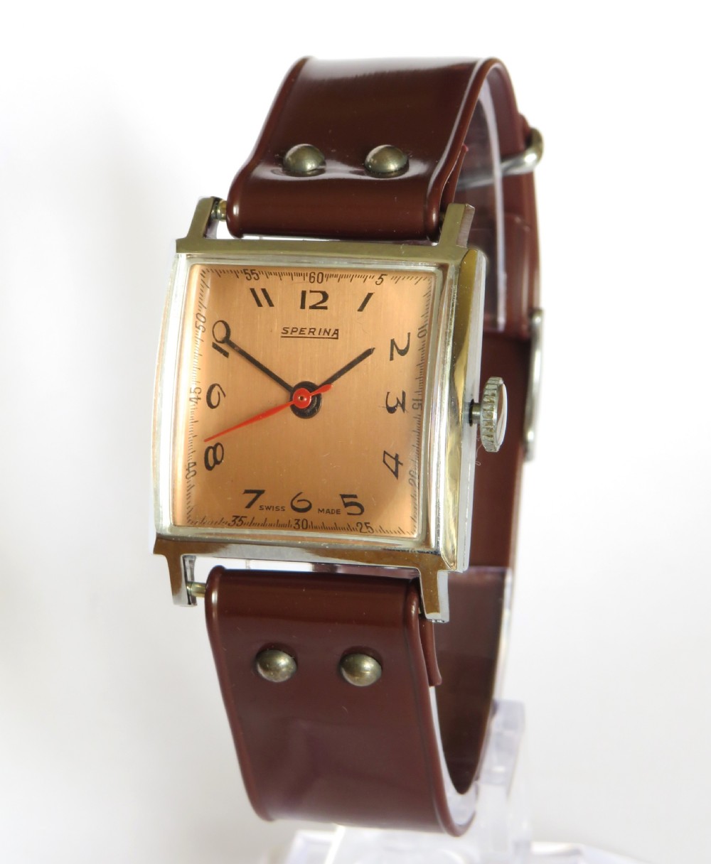 A gents 1940s Sperina wristwatch featuring a square copper-coloured dial, black Arabic numerals, a red second hand, and a brown riveted strap.