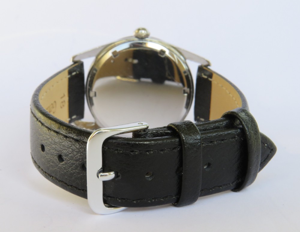 A vintage 1960s Girard-Perregaux wristwatch featuring a champagne dial, silver-tone stainless steel case, baton hour markers, and a black leather strap. View IV