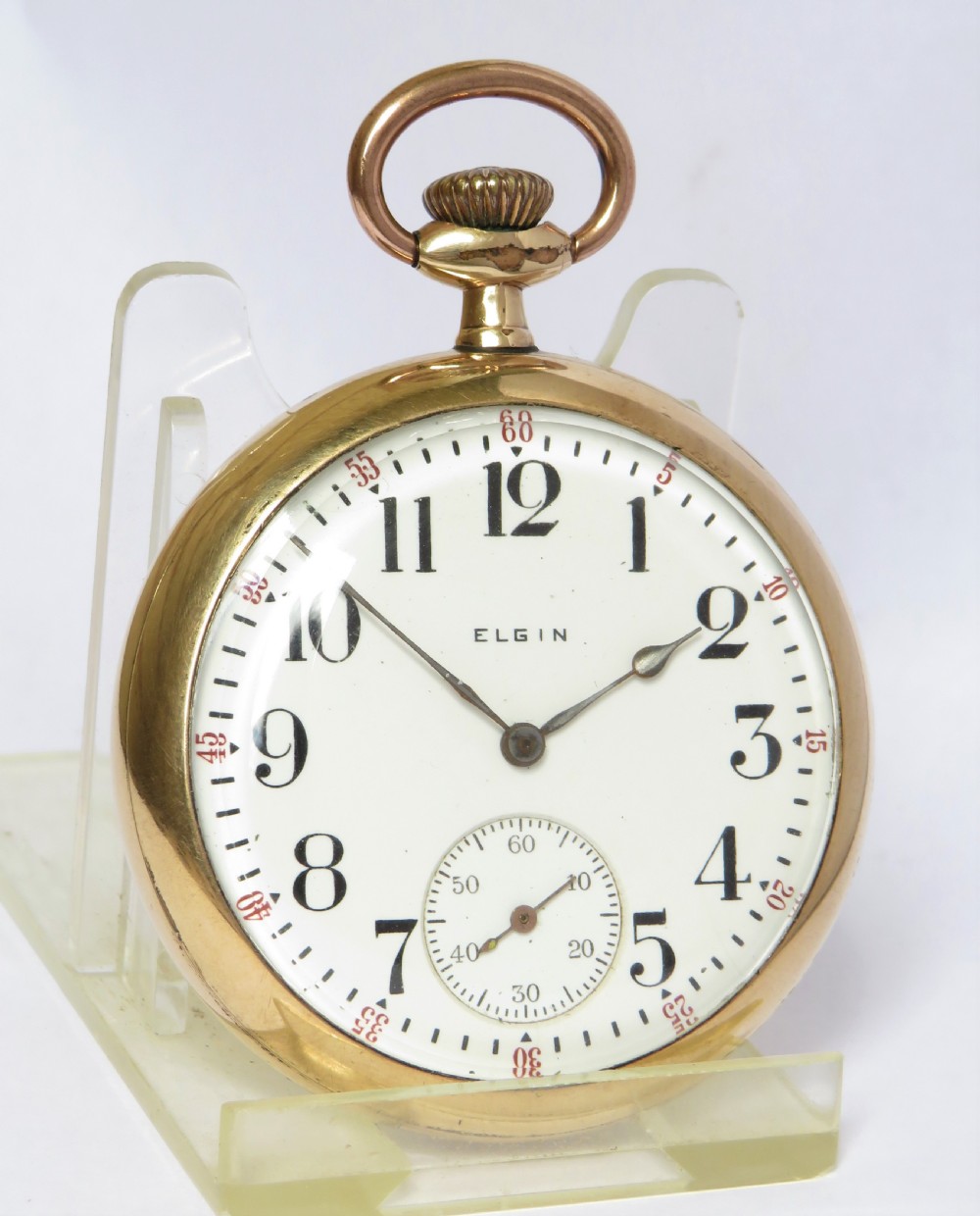 An antique open-face Elgin pocket watch featuring a gold-toned case, white enamel dial with black Arabic numerals, red minute markers, and a sub-seconds dial at six oclock. View III