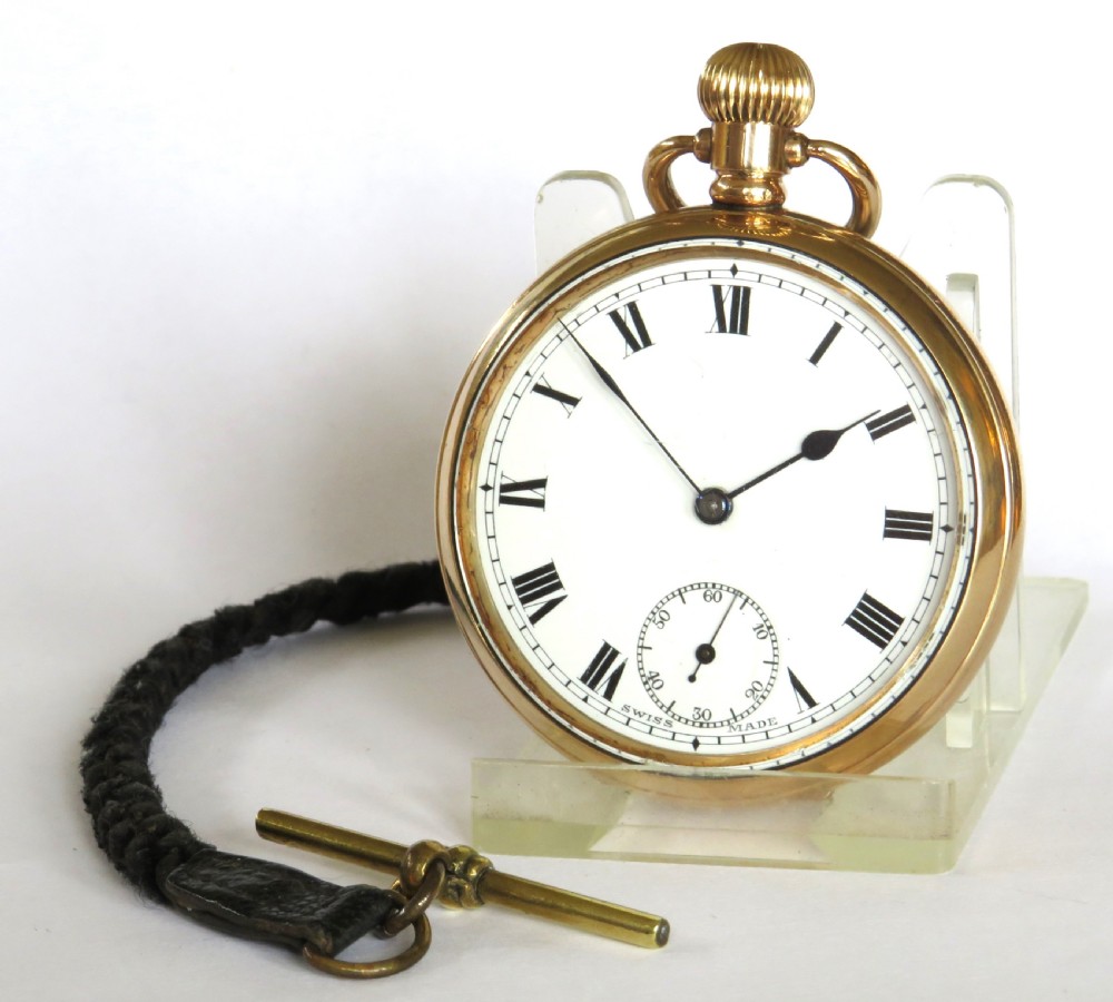 An open-face gold pocket watch featuring a white dial with Roman numerals and an accompanying black braided strap with a brass T-bar.