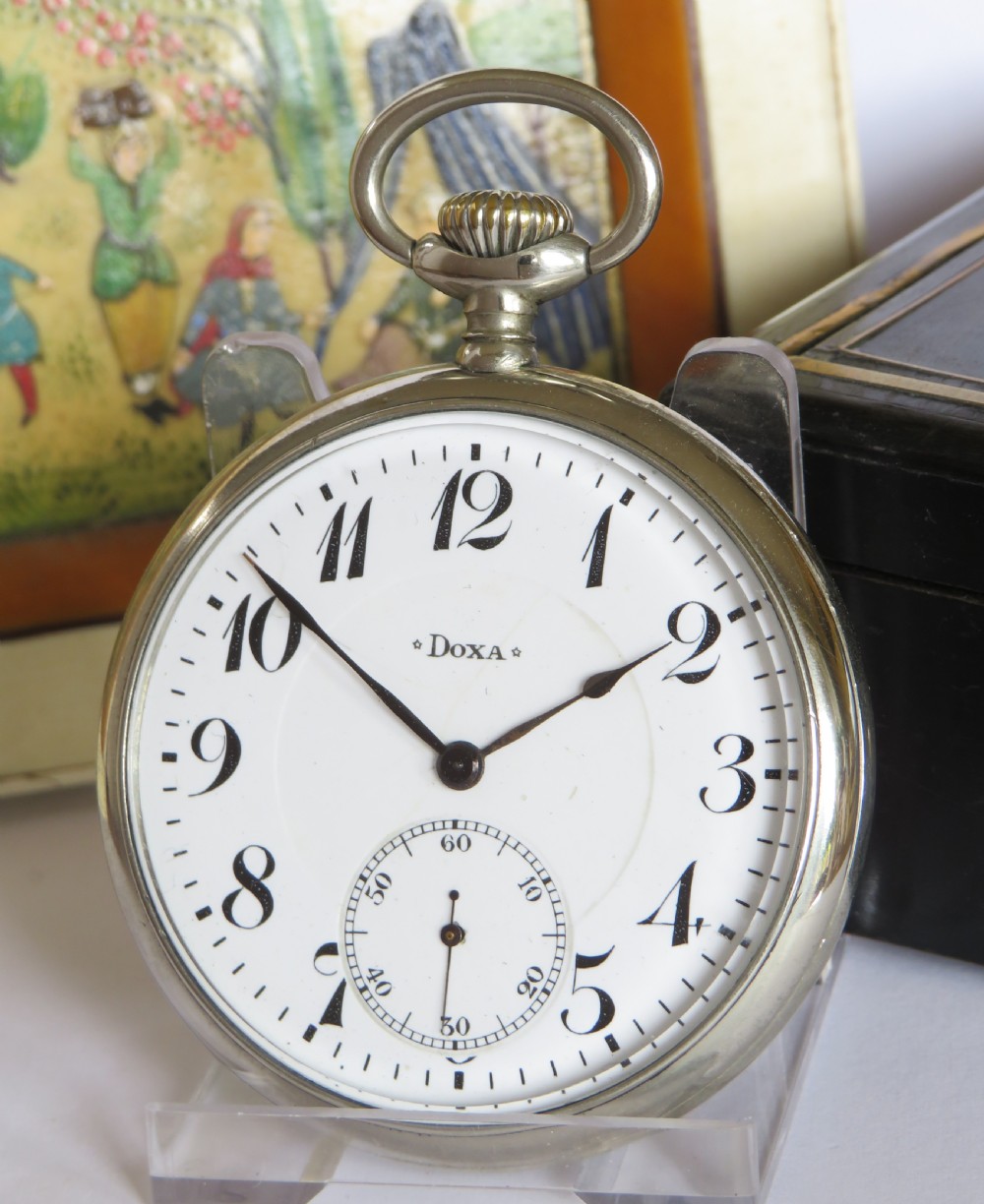 An open-face antique pocket watch featuring a white enamel dial with black Arabic numerals, a sub-seconds dial, and a polished silver-toned casing.