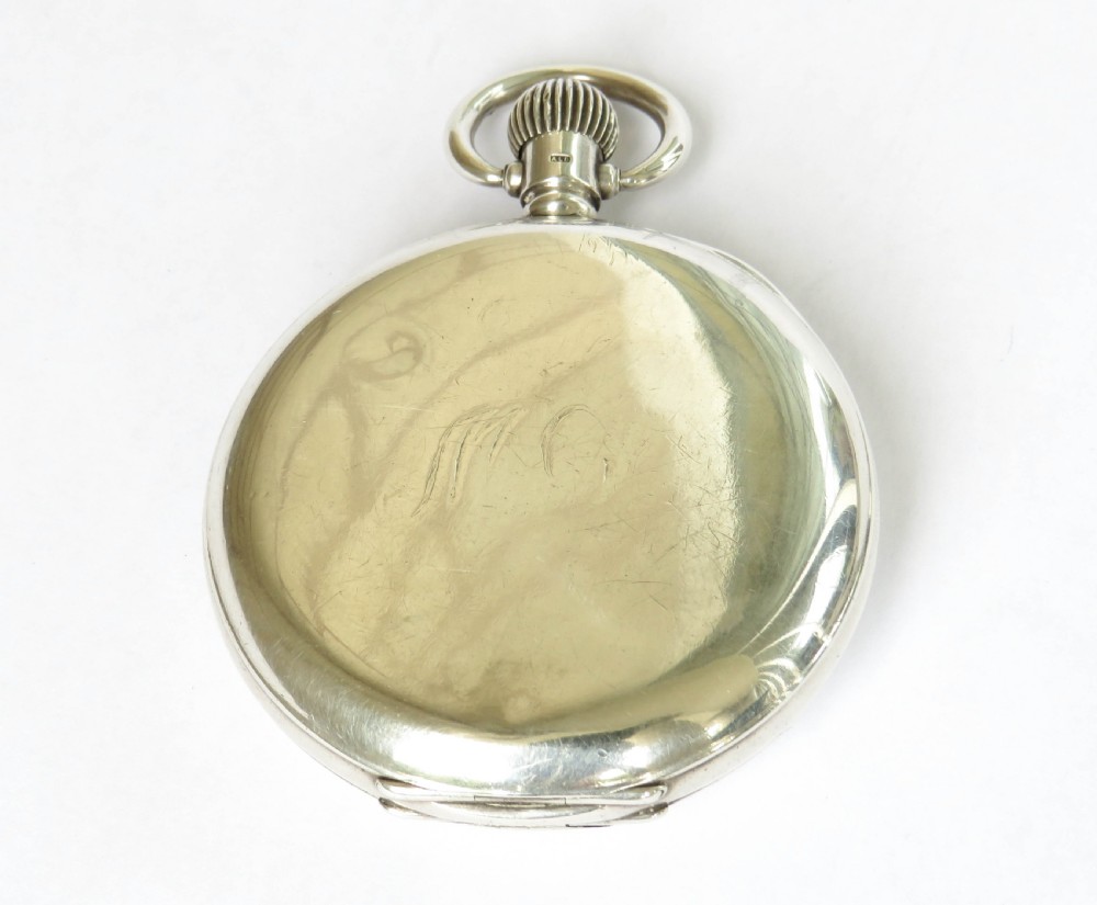 An open silver half hunter pocket watch featuring a white enamel dial with black Arabic numerals, a sub-seconds dial, and a polished silver casing. View V