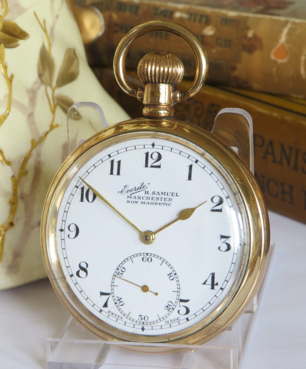 A 1930s gold-toned open-face pocket watch displaying a white dial with black Arabic numerals and a sub-seconds dial at six oclock.