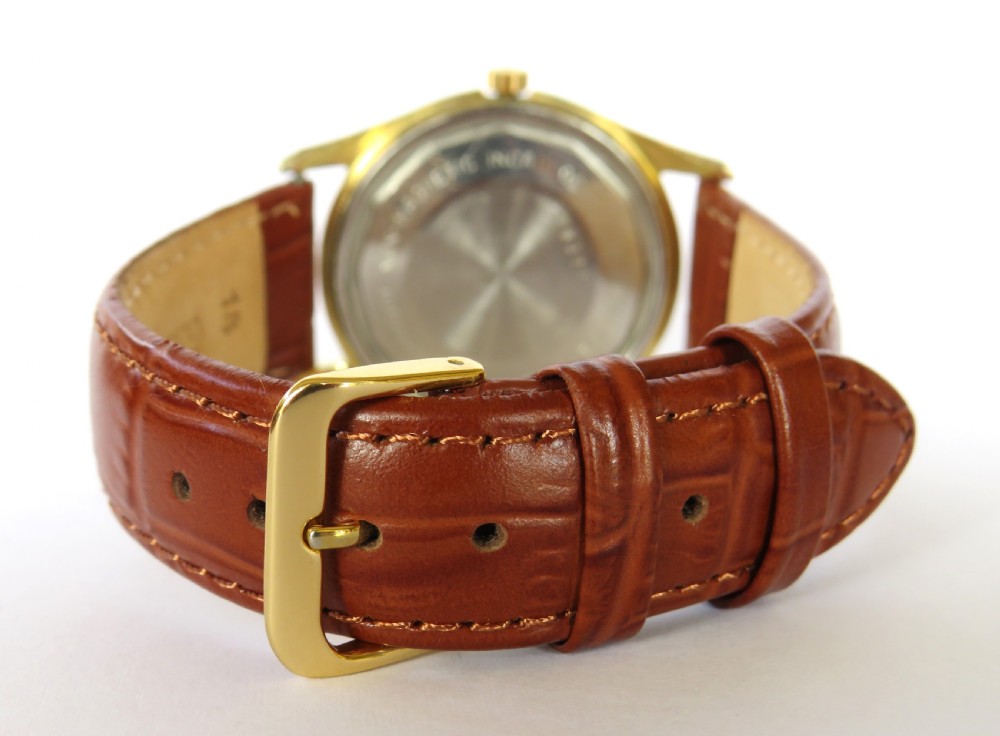A 1950s gents Baume Bimatic wrist watch with a gold-plated round case, champagne dial, and textured brown leather strap. View V