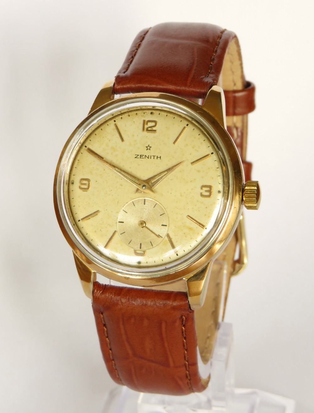 A vintage 1960s Zenith Stellina mechanical wristwatch featuring a gold-plated case, champagne sub-seconds dial, and a brown crocodile-grain leather strap.