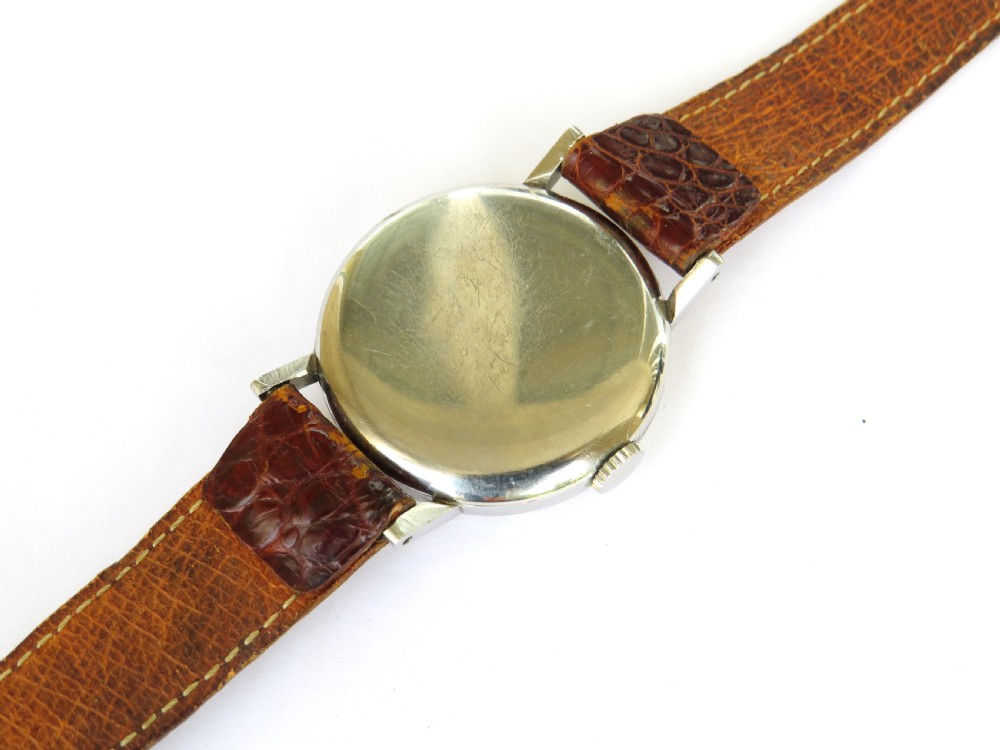 A 1944 vintage gentlemans Omega wristwatch featuring a round silver-tone case, cream dial with black Roman numerals, a sub-seconds dial at six oclock, and a textured brown leather strap. View IV
