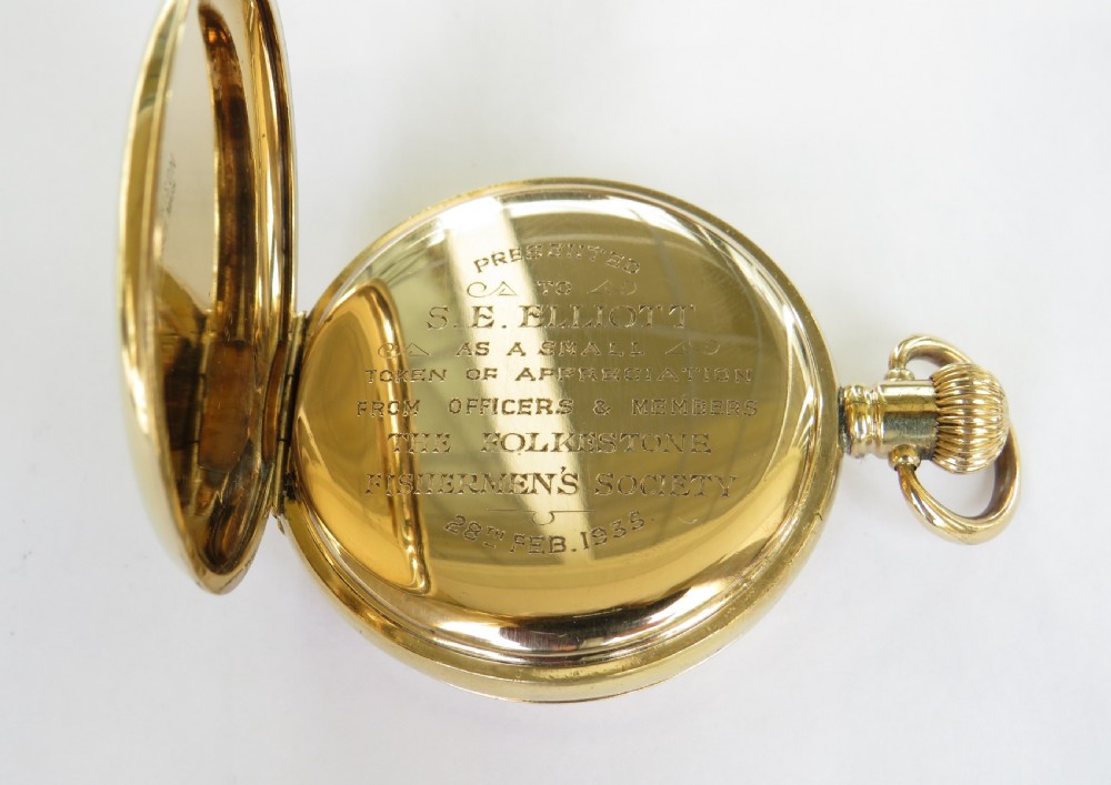 A gold-toned 1930s half hunter pocket watch with outer Roman numerals around a central window showing internal hands. View II