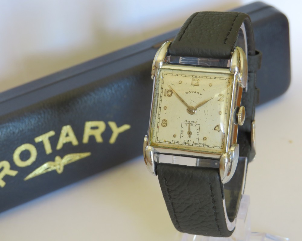 A 1950s gents Rotary wristwatch featuring a rectangular silver-tone case, cream dial with Arabic numerals, sub-seconds dial, and a black leather strap.
