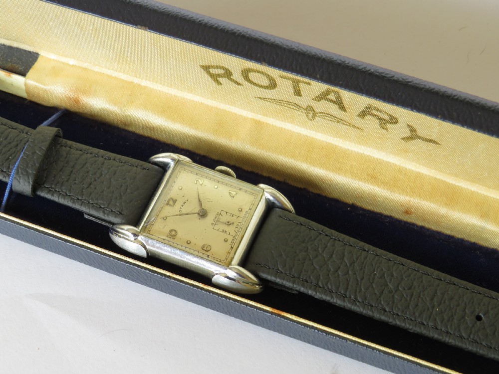 A 1950s gents Rotary wristwatch featuring a rectangular silver-tone case, cream dial with Arabic numerals, sub-seconds dial, and a black leather strap. View II