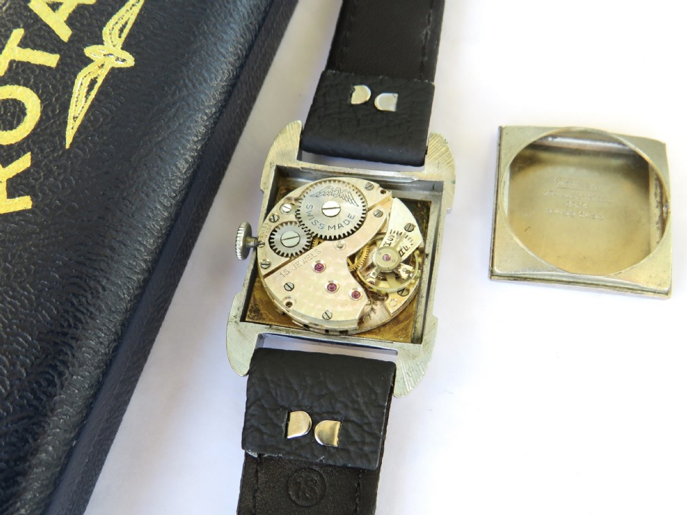A 1950s gents Rotary wristwatch featuring a rectangular silver-tone case, cream dial with Arabic numerals, sub-seconds dial, and a black leather strap. View III